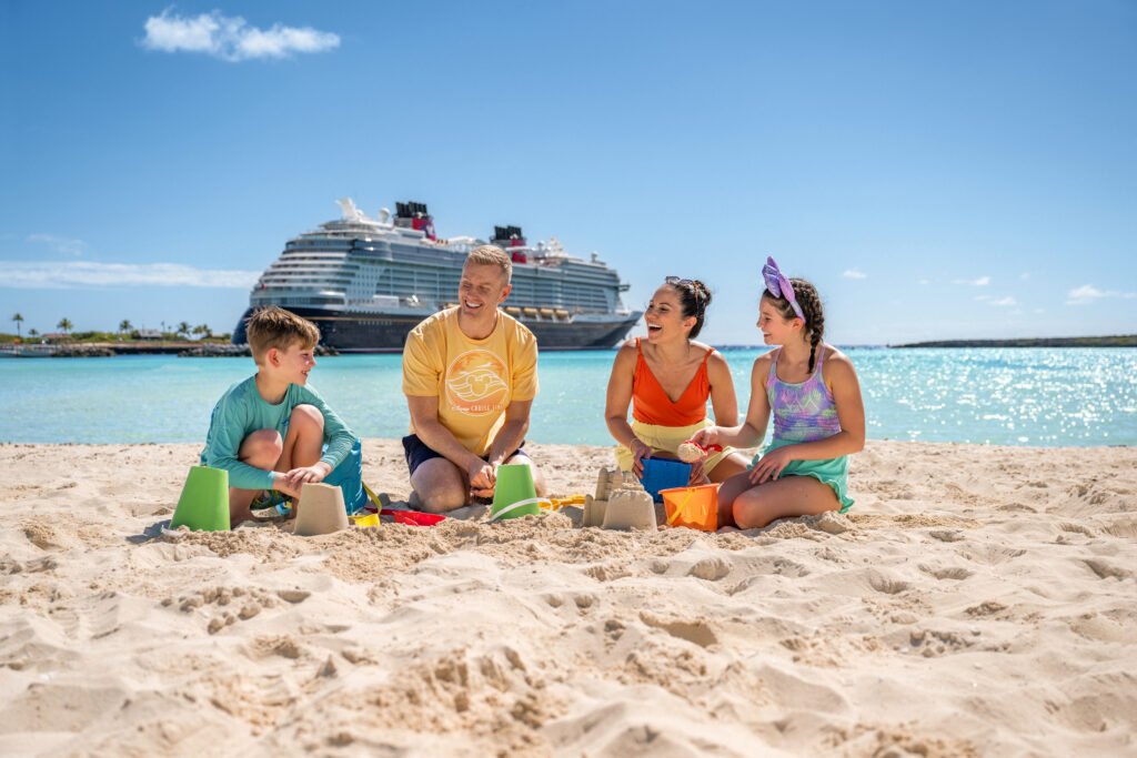 A family building sandcastles at Castaway Cay with a Disney cruise ship behind them